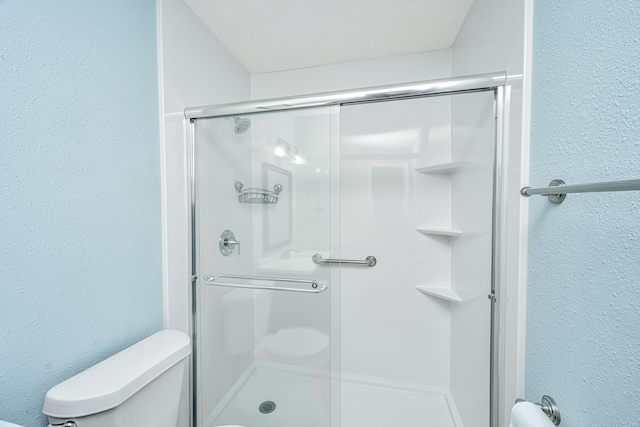 bathroom with a shower with door and toilet