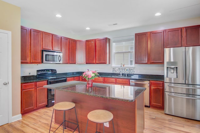 520 Crossland Dr, Moncks Corner, SC 29461 - kitchen featuring appliances with stainless steel finishes, dark brown cabinets, light wood-type flooring, a center island, and a breakfast bar area