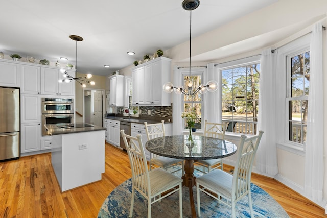 dining room featuring a chandelier, light wood-style floors, and baseboards