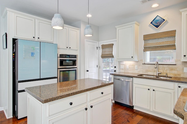 kitchen featuring dark stone counters, white cabinetry, a sink, appliances with stainless steel finishes, and backsplash