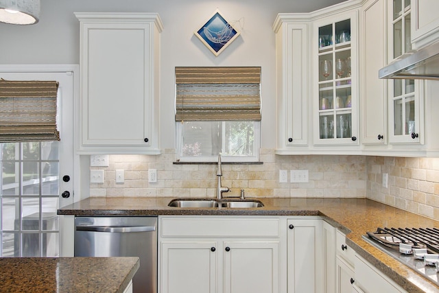 kitchen with a sink, dark stone countertops, stainless steel appliances, white cabinetry, and tasteful backsplash