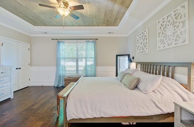 bedroom with crown molding, dark wood finished floors, wainscoting, and a raised ceiling