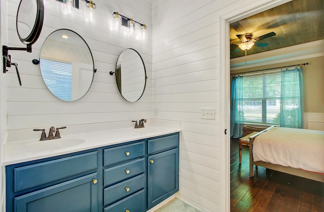 full bath with a sink, wood-type flooring, a ceiling fan, and wooden walls