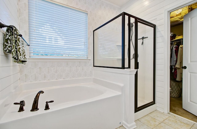 bathroom featuring crown molding, a walk in closet, tile patterned flooring, a bath, and a stall shower