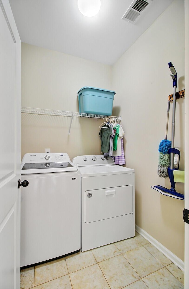 laundry area with laundry area, visible vents, light tile patterned flooring, baseboards, and separate washer and dryer