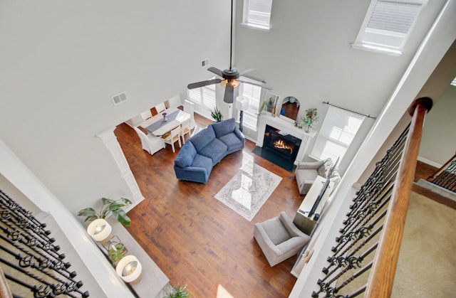 living area featuring visible vents, a fireplace with flush hearth, a high ceiling, and a wealth of natural light