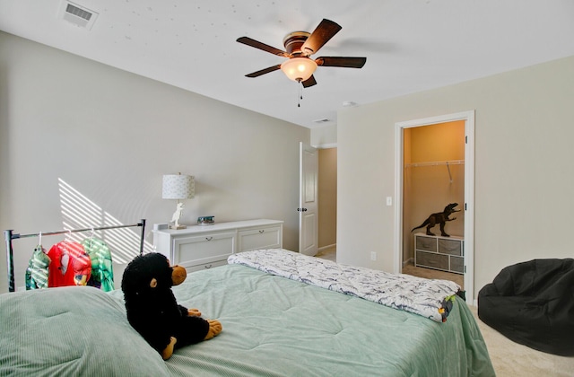 carpeted bedroom featuring ceiling fan, visible vents, a walk in closet, and a closet