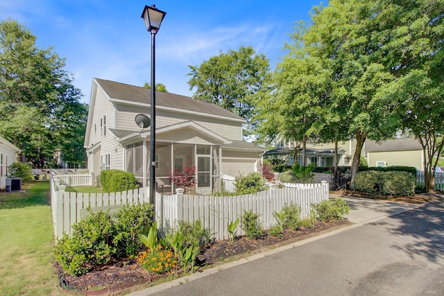 bungalow-style house featuring central AC, a fenced front yard, a sunroom, and a garage