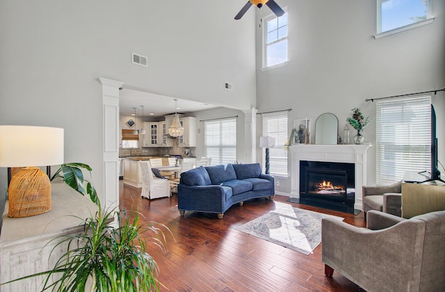 living area with ornate columns, a high ceiling, visible vents, and a wealth of natural light