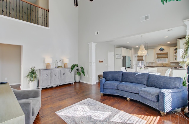 living area featuring baseboards, visible vents, dark wood finished floors, and a towering ceiling