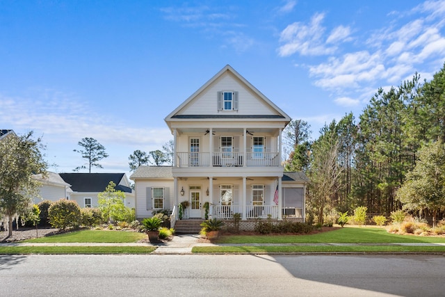 neoclassical home featuring ceiling fan, a balcony, a front lawn, and covered porch