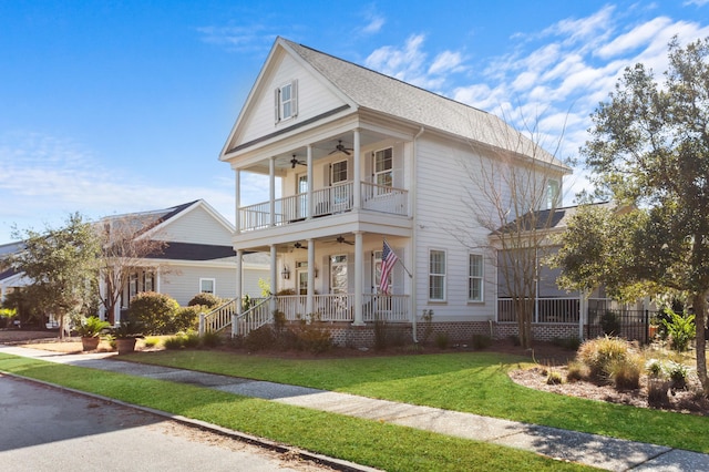 greek revival house featuring ceiling fan, a balcony, a front lawn, and covered porch