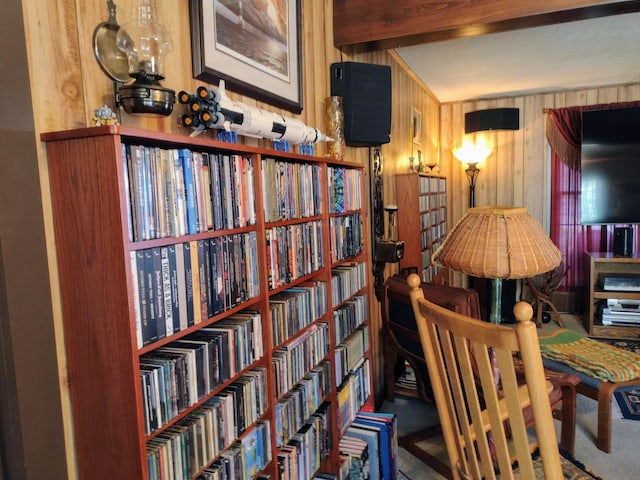 sitting room featuring wood walls, carpet flooring, and bookshelves