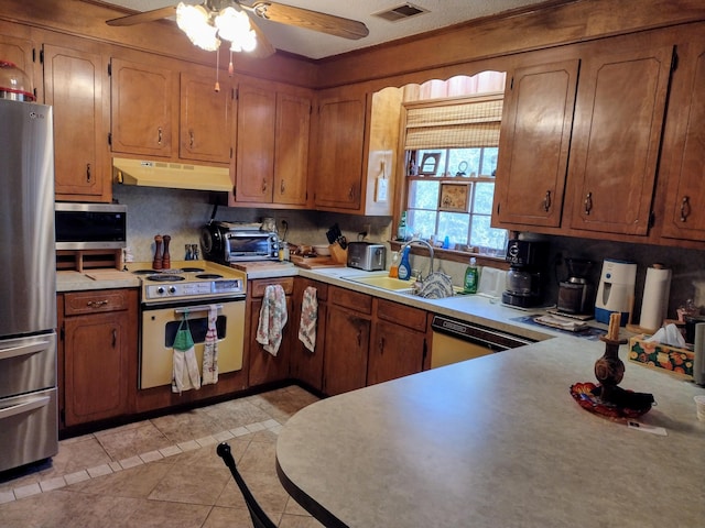 kitchen featuring visible vents, a toaster, stainless steel appliances, light countertops, and under cabinet range hood