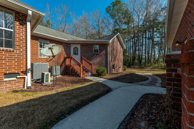 view of side of home featuring brick siding and central AC unit