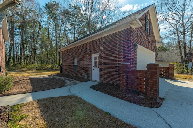 view of property exterior with concrete driveway, brick siding, and an attached garage