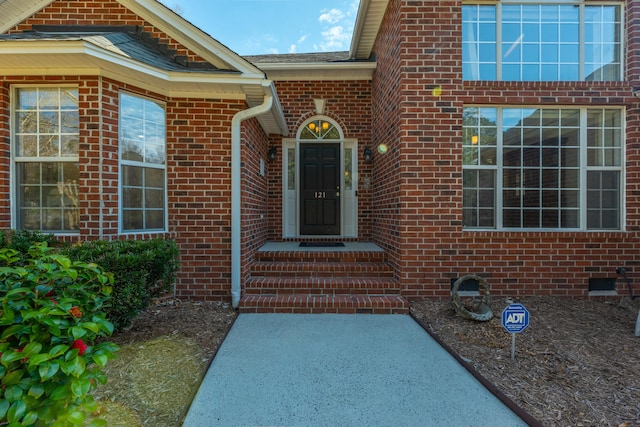 entrance to property featuring crawl space and brick siding