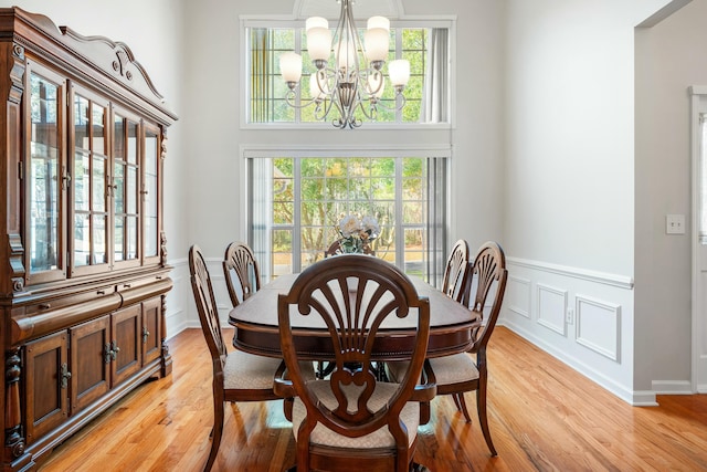 dining room featuring a chandelier, light wood-type flooring, and a wainscoted wall