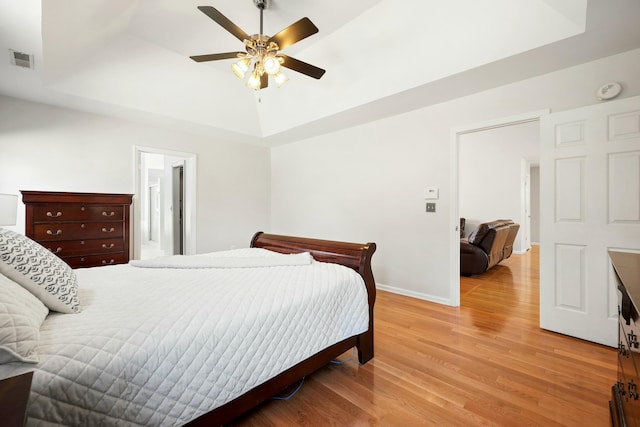 bedroom featuring light wood-style floors, visible vents, and a tray ceiling