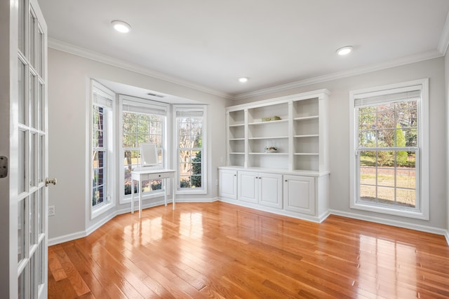 interior space with light wood-style floors, crown molding, and baseboards