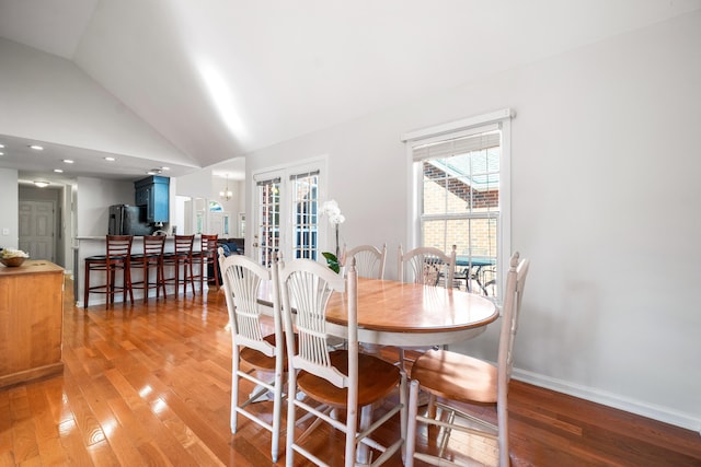 dining area featuring french doors, an inviting chandelier, high vaulted ceiling, light wood-type flooring, and baseboards