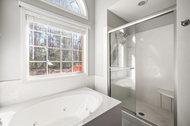 full bath featuring a healthy amount of sunlight, a shower stall, and a jetted tub