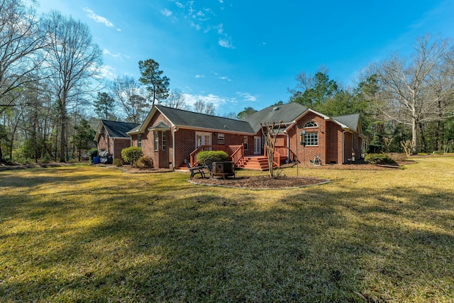 rear view of property featuring a deck, a lawn, and brick siding