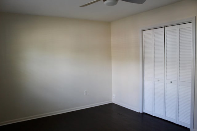 unfurnished bedroom featuring ceiling fan, dark hardwood / wood-style flooring, and a closet