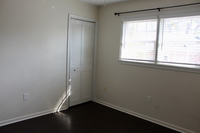 unfurnished bedroom with dark wood-type flooring and a closet