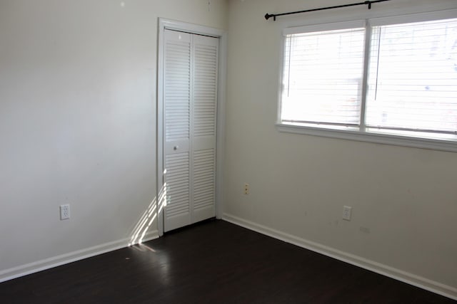 unfurnished bedroom with dark hardwood / wood-style flooring and a closet