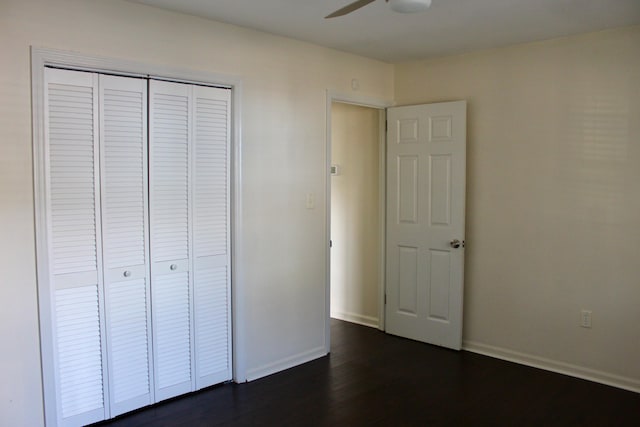 unfurnished bedroom featuring dark wood-type flooring, a closet, and ceiling fan