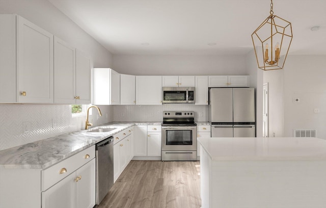 5748 Pilgrim Ave Unit D, Hanahan, SC 29410 - kitchen featuring appliances with stainless steel finishes, a sink, light wood-style floors, decorative backsplash, and white cabinetry