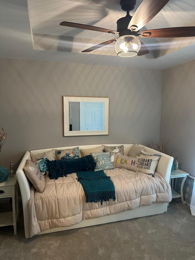 carpeted bedroom with ceiling fan and a raised ceiling