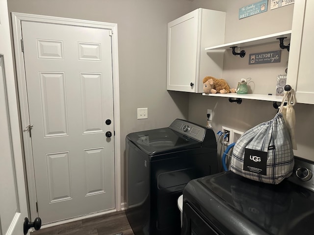 washroom featuring washing machine and dryer, dark hardwood / wood-style flooring, and cabinets