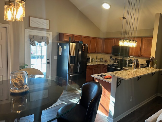 kitchen featuring decorative light fixtures, stainless steel refrigerator with ice dispenser, backsplash, and kitchen peninsula