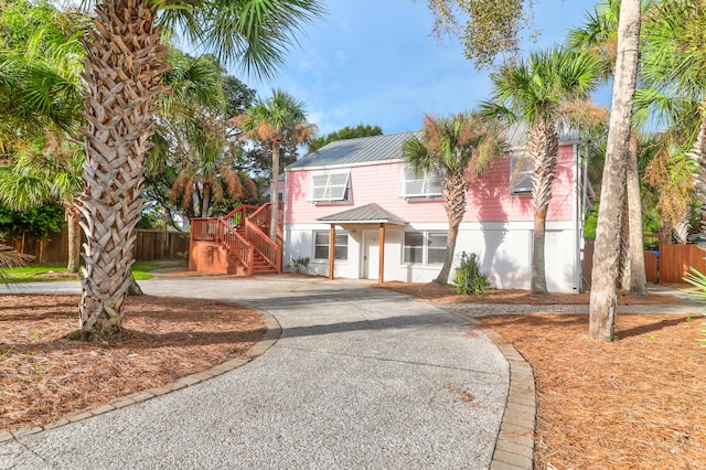 view of front of house with metal roof, driveway, stairway, and fence