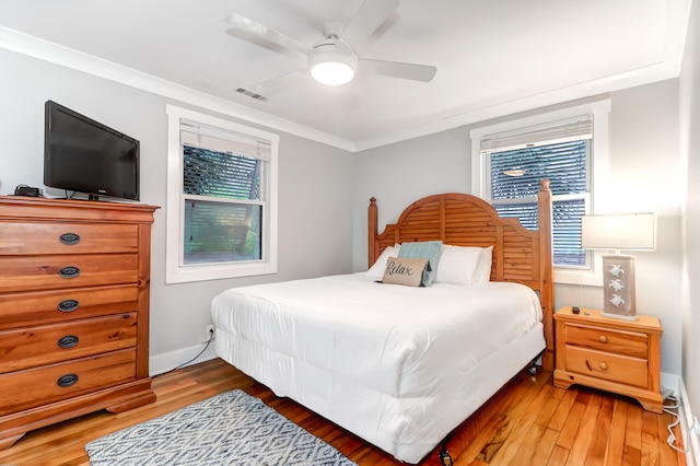 bedroom featuring light wood finished floors, baseboards, visible vents, a ceiling fan, and ornamental molding