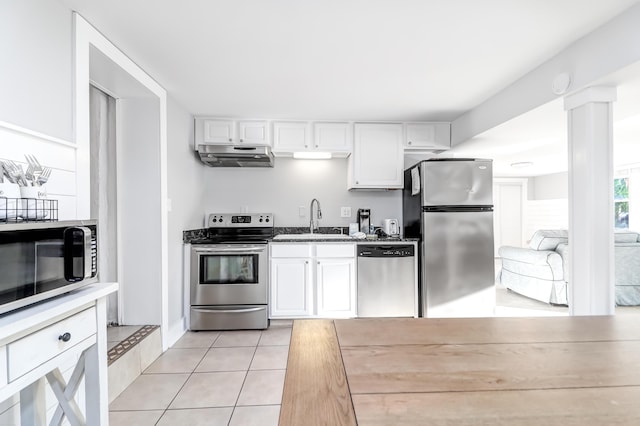 kitchen featuring light tile patterned floors, appliances with stainless steel finishes, a sink, and white cabinets