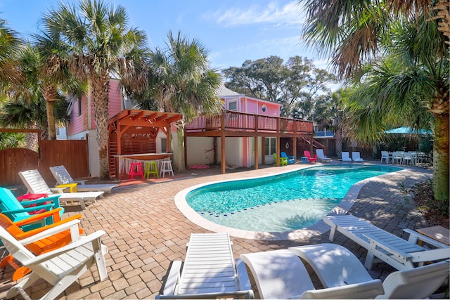 view of pool featuring a patio area, a fenced backyard, a deck, and outdoor dry bar