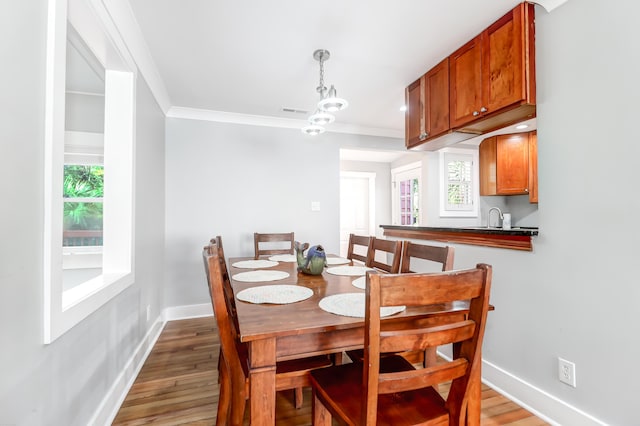 dining area with ornamental molding, light wood-type flooring, and baseboards