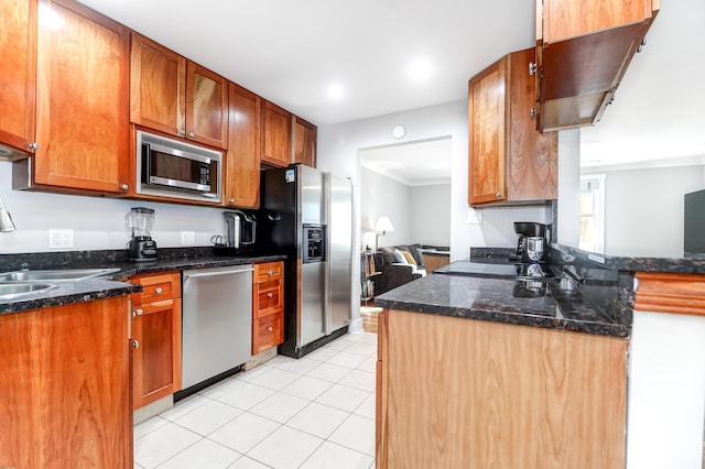 kitchen with dark stone counters, stainless steel appliances, light tile patterned flooring, and a sink