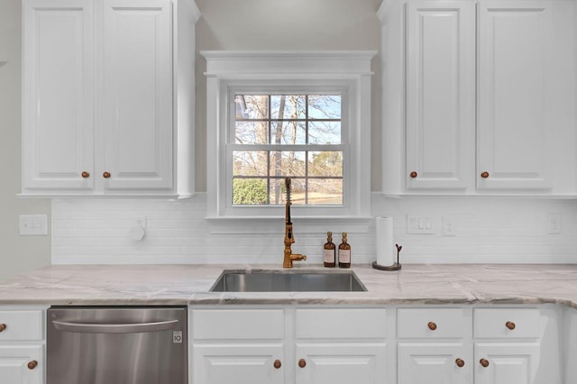 kitchen with tasteful backsplash, white cabinetry, dishwasher, sink, and light stone countertops