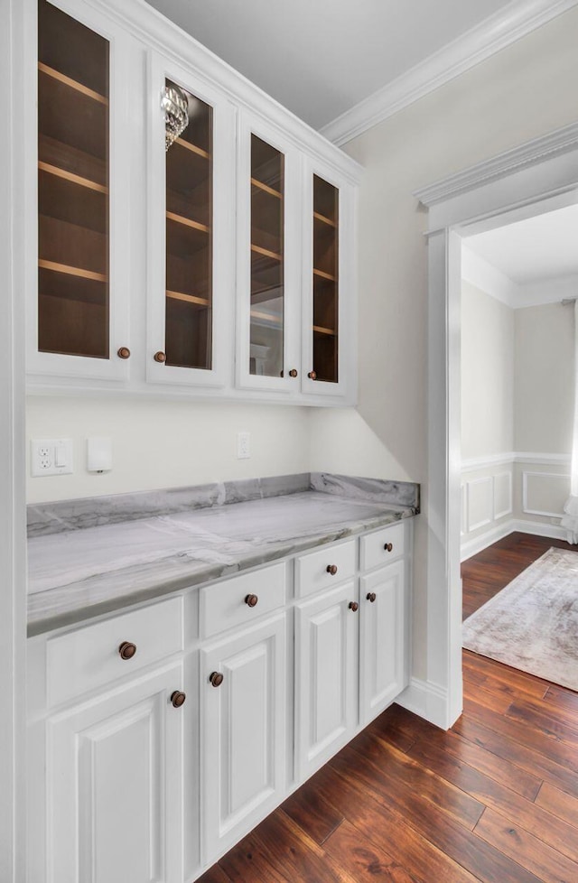 bar featuring white cabinetry, ornamental molding, dark hardwood / wood-style floors, and light stone countertops