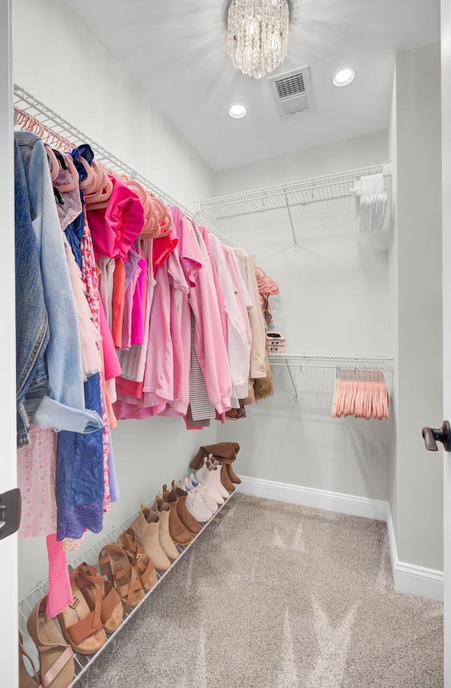 walk in closet featuring carpet floors and a notable chandelier