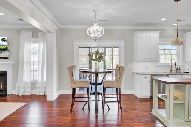 dining area with ornamental molding, sink, dark wood-type flooring, and a notable chandelier