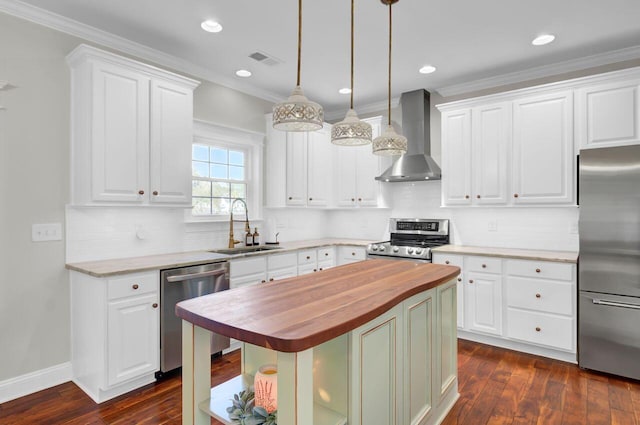 kitchen featuring wood counters, wall chimney exhaust hood, sink, a kitchen island, and stainless steel appliances