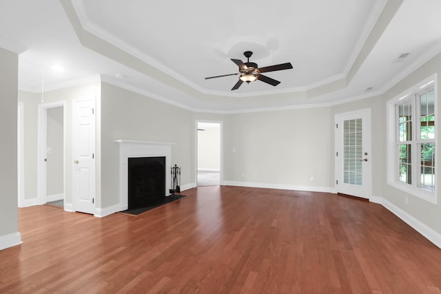 unfurnished living room featuring hardwood / wood-style flooring, ceiling fan, ornamental molding, and a tray ceiling