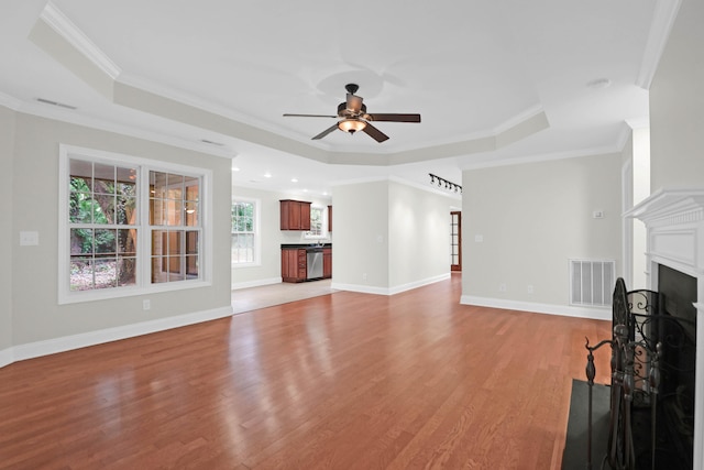 unfurnished living room with a tray ceiling, light hardwood / wood-style flooring, ceiling fan, and ornamental molding