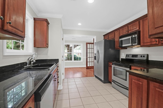 kitchen featuring sink, crown molding, dark stone countertops, light tile patterned floors, and stainless steel appliances