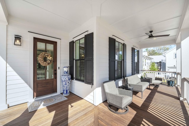 wooden terrace with an outdoor living space, a ceiling fan, and covered porch